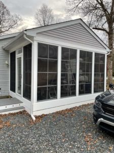 Three season room with white trim on gray sided home