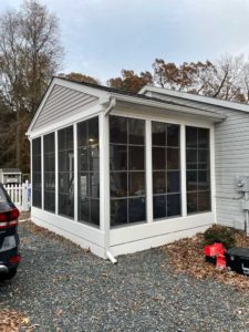 Three season room on gray home with white trim