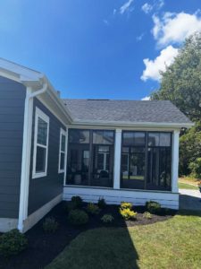 Side view of bronze three season room on blue home with white trim