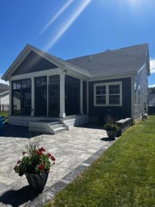 Screened porch with white trim on home with blue vinyl siding