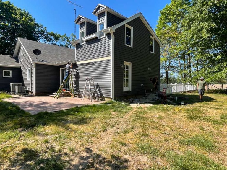 Before pic of gray house prior to install of white pergola and deck with white rails