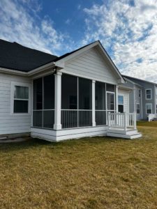 Screened porch with platform and steps with white trim on gray home