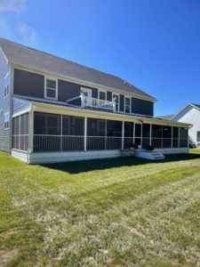 Large screened porch with white trim on blue home with second level balcony