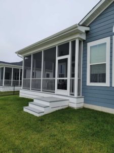 Screened porch with gray platform and steps on blue vinyl sided home