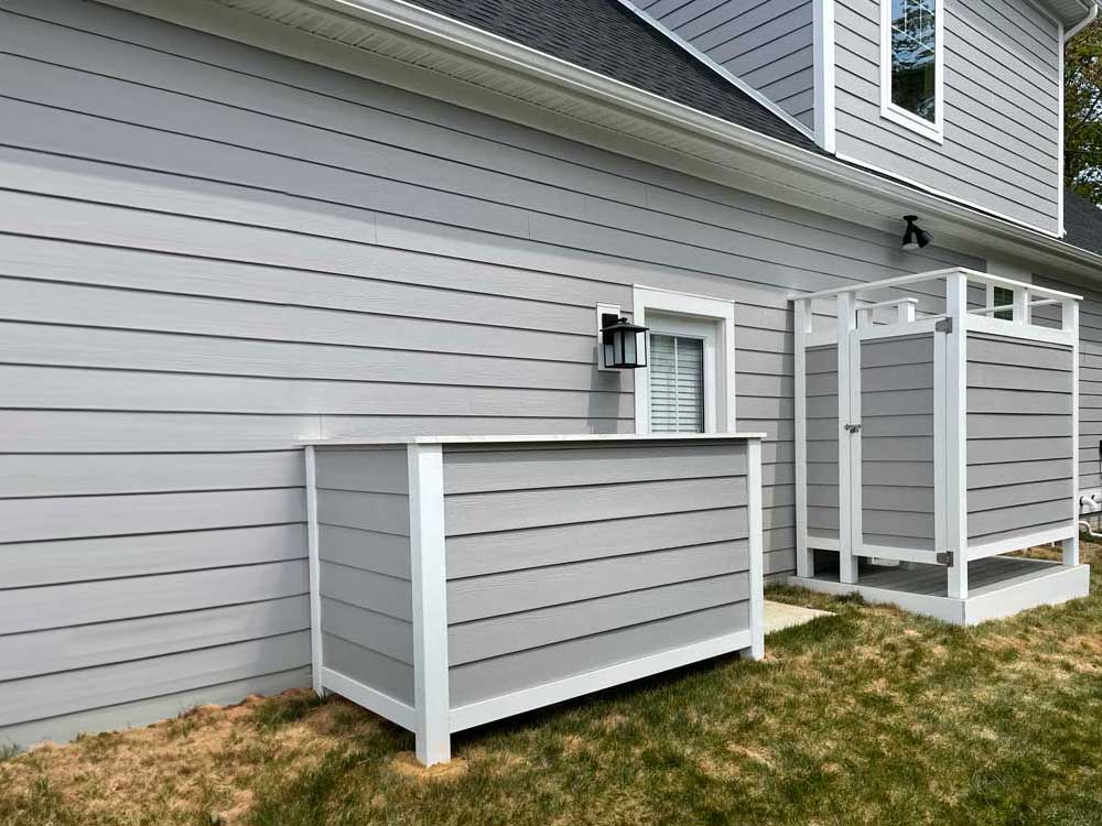 Gray vinyl shower stall and trash enclosure to match gray vinyl siding on home